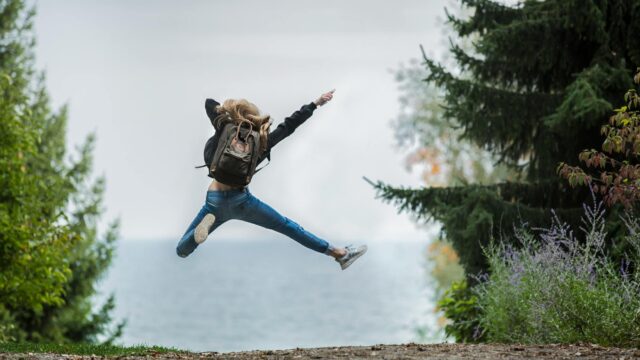 woman jumping wearing green backpack