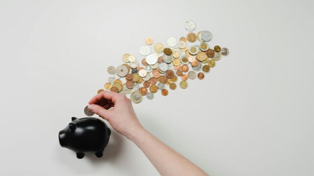 person putting coin in a piggy bank