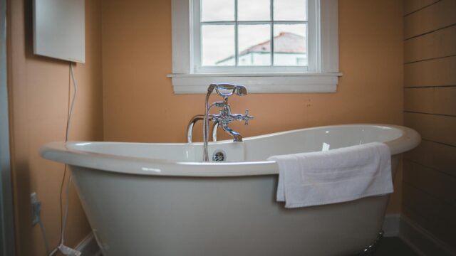 photo of ceramic bathtub near window