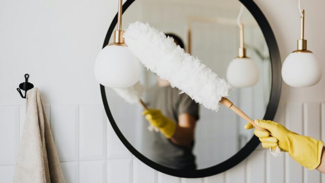 crop woman dusting lamp during housework