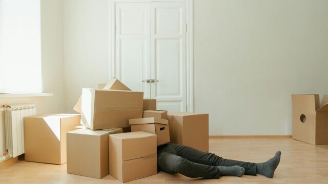 person in black leather boots lying on brown cardboard boxes