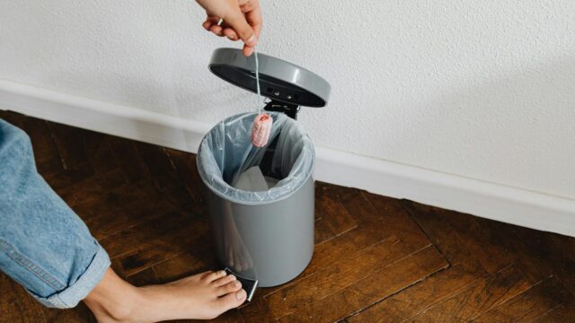 person throwing a tampon in a trash bin