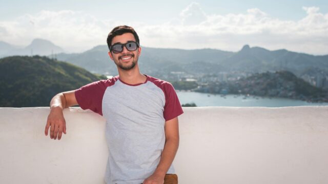 man wearing gray and red crew neck shirt smiling