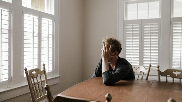 photo of man leaning on wooden table