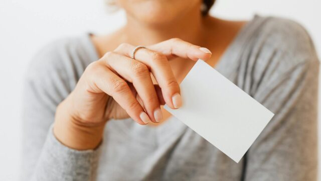 woman in gray long sleeves shirt holding a small piece of white paper