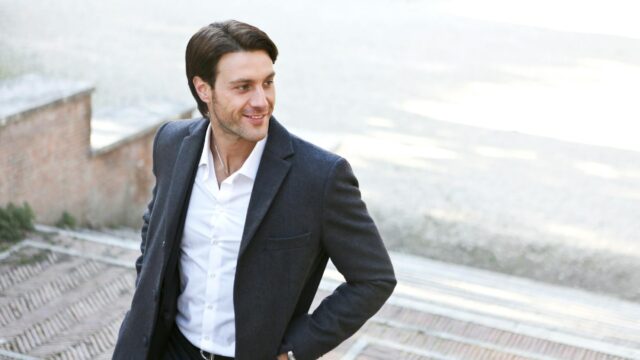 man in white dress shirt and black blazer standing outside building