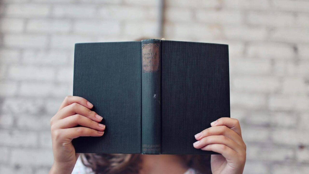 selective focus photography of woman holding book